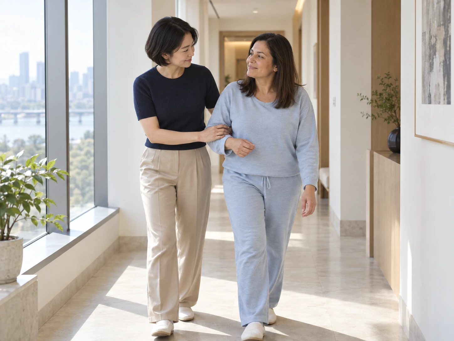 A care professional offering steady support as a guest walks through a sunlit corridor.